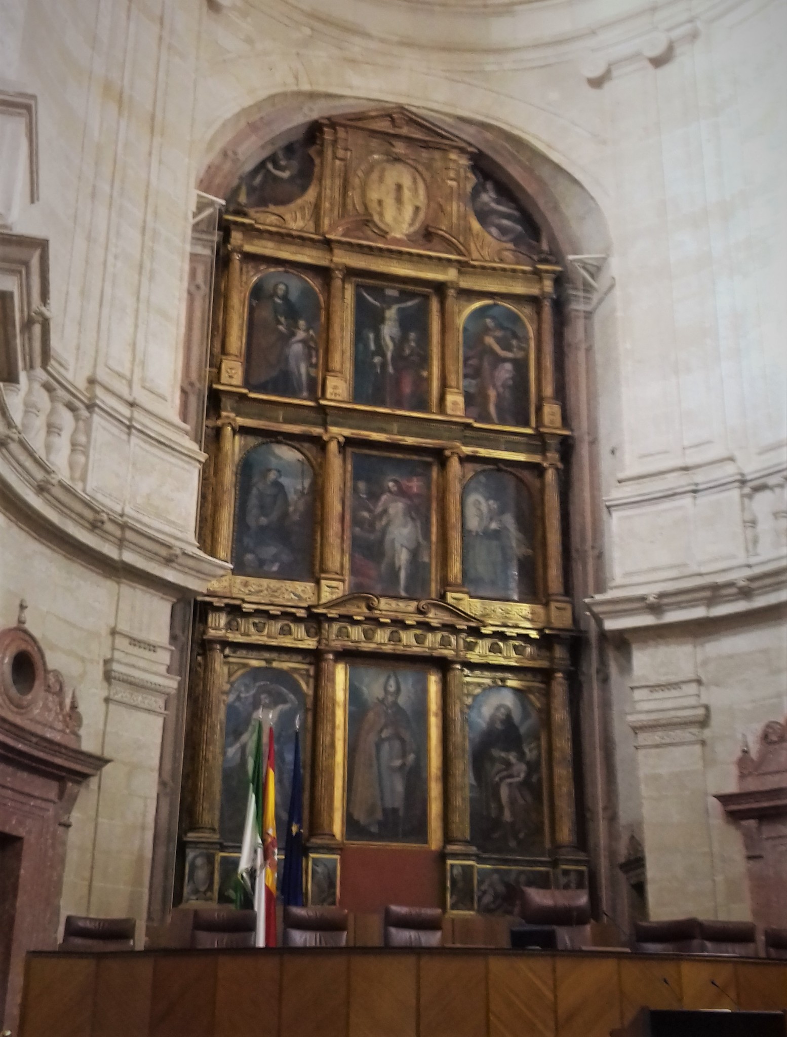 Retablo de la antigua iglesia renacentista, desacralizada, en las sesiones parlamentarias, se cubre con el escudo de Andalucía.